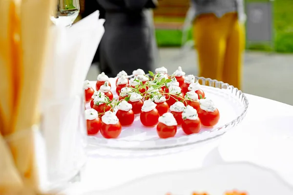 Appetizers with red tomato and white cheese on top stand on a transparent plate — Stock Photo, Image