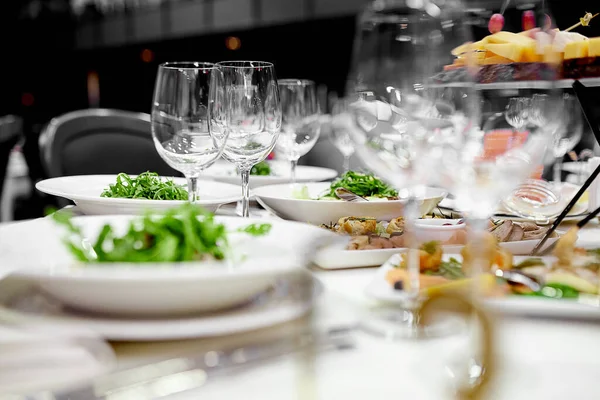 सफेद मेजवानी के साथ उत्सव की मेज पर क्रिस्टल वाइन ग्लास और एक ग्रीन सब्जी सलाद हैं — स्टॉक फ़ोटो, इमेज