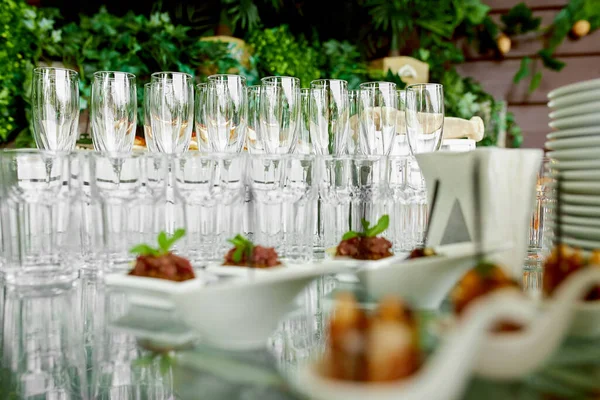 empty, clean, crystal champagne glasses and crystal glasses for water stand on a serving table