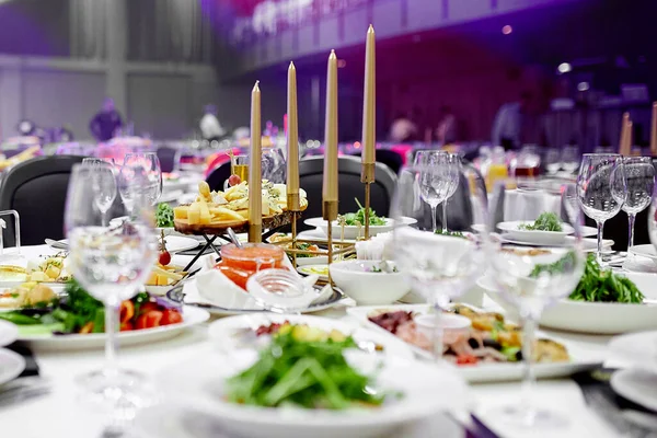 Auf dem festlichen Tisch mit weißen Tischdecken stehen kristallene Weingläser und ein grüner Gemüsesalat lizenzfreie Stockfotos