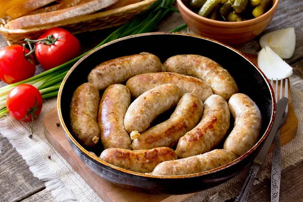 Homemade meat raw sausage on a cast iron frying pan, vegetables,
