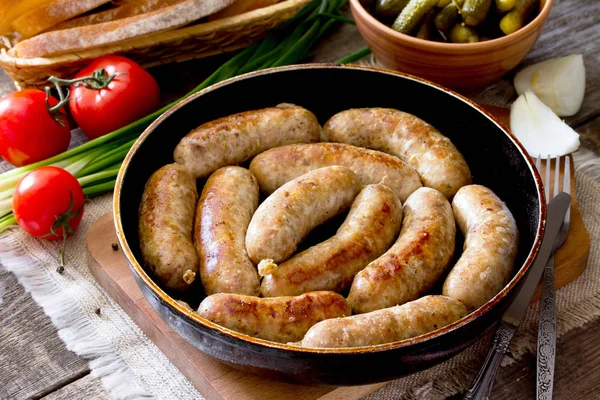 Salsicha crua de carne caseira em uma frigideira de ferro fundido, legumes , — Fotografia de Stock