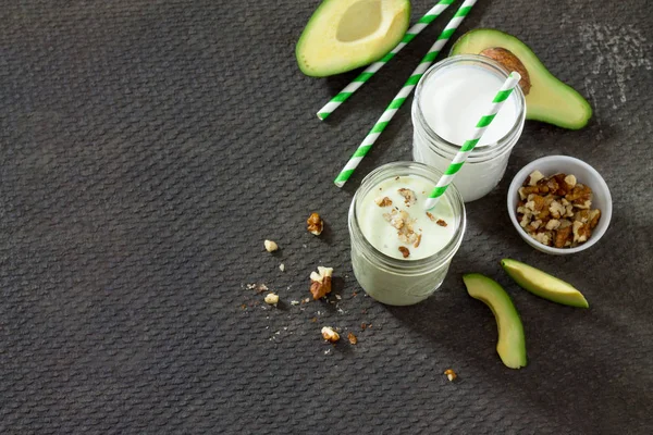 Healthy green cocktail with avocado and walnuts in a bank of gla