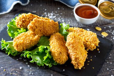 Sıcak, çıtır tavuk ve kayrak bir tahta üzerinde taze marul. Aperatif SK