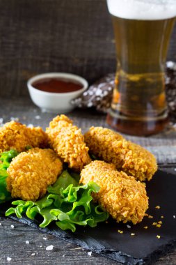 Baharatlı kızarmış tava tavuk kanatları ve bir bardak bira bir woode üzerinde