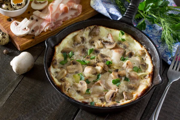 Omelette from quail eggs with ham and bacon in a cast iron fryin — Stock Photo, Image