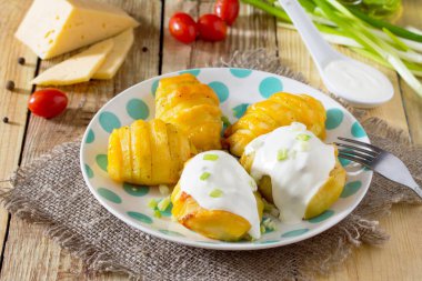 Üzerinde krema sos ve yeşillik eşliğinde peynirli patates pişmiş bir