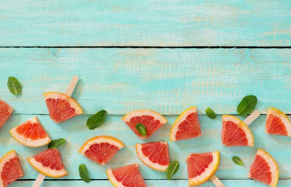 Scheiben rotes Grapefruit Eis am Stiel auf einem Vintage-Holzgrund — Stockfoto