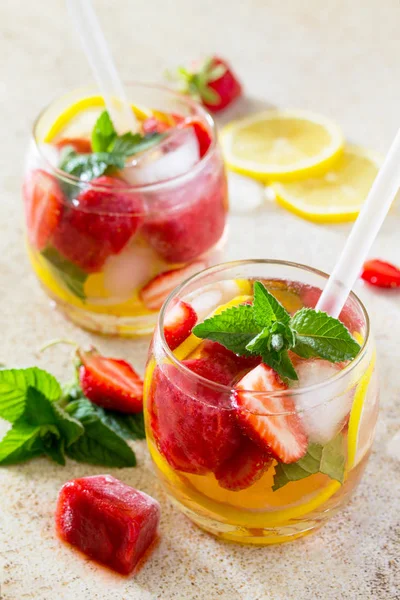 A refreshing summer drink with ice and strawberries on a stone b — Stock Photo, Image