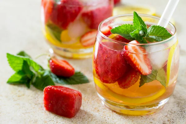 A refreshing summer drink with ice and strawberries on a stone b — Stock Photo, Image