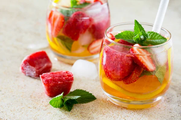 A refreshing summer drink with ice and strawberries on a stone b — Stock Photo, Image