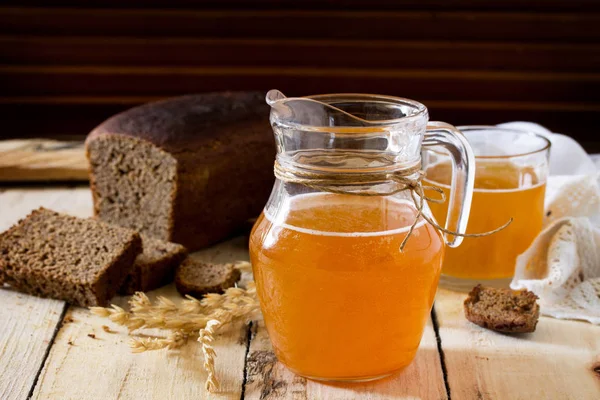 Traditionele Russische koude rogge drankje Kvas in een glas en een kruik op — Stockfoto