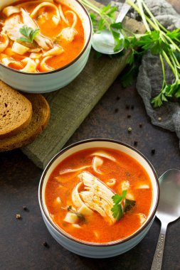 Domates çorbası ile makarna ve tavuk bir karanlık bir kabın içinde TZB taş