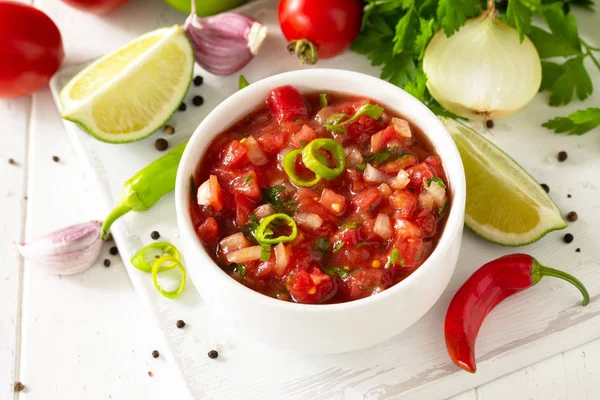 Traditional mexican homemade salsa sauce and ingredients on a wh