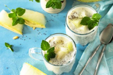 Sağlıklı bir bardakta puding Chia, kavun ve mavi taşın üstünde