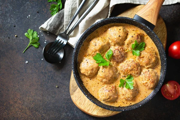 Albóndigas en crema agria y salsa de tomate en una sartén en un ston oscuro —  Fotos de Stock