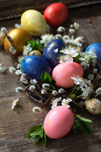 Цветные пасхальные яйца в гнезде с весенними цветами на сером wo — стоковое фото