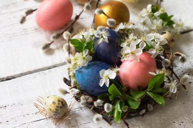 Colored Easter eggs, willow branches and spring flowers on a whi