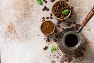Morning coffee concept. Turkish coffee in Turk and coffee beans on a stone or slate countertop. Top view flat lay background. Copy space. clipart