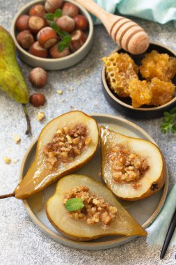 Sağlıklı diyet tatlı. Fındıklı fırında armut, bal ve granola kayrak, taş ya da beton arka planda.