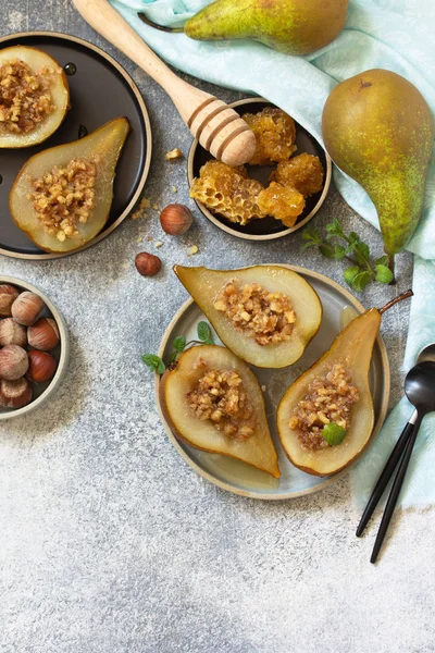 Healthy diet dessert. Baked pears with hazelnuts, honey and granola on a slate, stone or concrete background. Top view flat lay background. Copy space