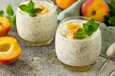 Doğal detoks, meyveli tatlı yakın plan, sağlıklı beslenme konsepti. Şeftalili yoğurtlu smoothie ya da cam kavanozda chia tohumları olan sütlü milkshake. Taş beton atölyesinde..