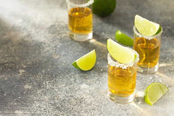Gold Tequila. Mexican Gold Tequila shot with lime and salt on a stone light concrete worktop. Copy space