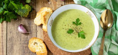 Vejetaryen yemeği. Köy masasında sarımsaklı kıtır ekmekle servis edilen lezzetli brokoli kremalı çorba. Pankart.