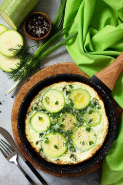 Kahvaltıda. Kabaklı yaz omleti ve bir taş ya da tahta masa üzerinde otlar. Üst görünüm düzlüğü. 