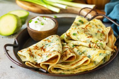 Atıştırmalık ya da yaz yemeği. Gri bir taşın üzerinde ekşi kremayla servis edilen kabaklı gözlemeler veya tahta tezgah.. 