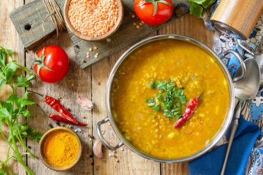 Hint yemeği, gerçek bir Hint yemeği. Geleneksel Hint baharatlı mercimek püre çorbası ve kırsal bir masada otlar. Üst görünüm düz arkaplan.