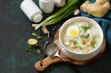 Arroz Caldo Çorbası. Zencefilli tavuklu sıcak çorba ve siyah tezgahta sarımsak. Boşluğu kopyala.