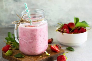 Doğal detoks, meyve tatlısı, sağlıklı beslenme konsepti. Çilekli yoğurtlu smoothie ya da cam kavanozdaki milkshake ya da kayrak taşı üzerinde.
