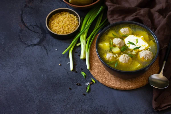 The concept of healthy and diet food. Russian or Ukrainian cuisine. Soup with meatballs, bulgur and pickled cucumbers on a dark stone table. Copy space — Stock Image Concept Healthy Diet Food Russian Ukrainian Cuisine Soup Meatballs Bulgur Royalty Free Stock Images