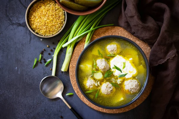 The concept of healthy and diet food. Russian or Ukrainian cuisine. Soup with meatballs, bulgur and pickled cucumbers on a dark stone table. Top view flat lay background. — Stock Image Concept Healthy Diet Food Russian Ukrainian Cuisine Soup Meatballs Bulgur Royalty Free Stock Images