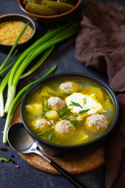 The concept of healthy and diet food. Russian or Ukrainian cuisine. Soup with meatballs, bulgur and pickled cucumbers on a dark stone table. — Stock Image Concept Healthy Diet Food Russian Ukrainian Cuisine Soup Meatballs Bulgur Stock Picture