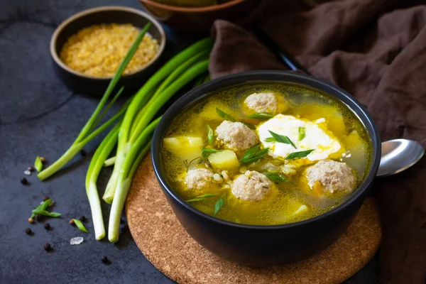 The concept of healthy and diet food. Russian or Ukrainian cuisine. Soup with meatballs, bulgur and pickled cucumbers on a dark stone table. — Stock Image Concept Healthy Diet Food Russian Ukrainian Cuisine Soup Meatballs Bulgur Royalty Free Stock Photos