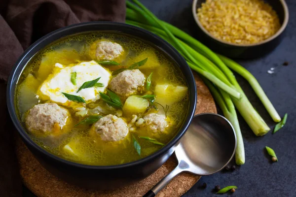 The concept of healthy and diet food. Russian or Ukrainian cuisine. Soup with meatballs, bulgur and pickled cucumbers on a dark stone table. — Stock Image Concept Healthy Diet Food Russian Ukrainian Cuisine Soup Meatballs Bulgur Stock Image