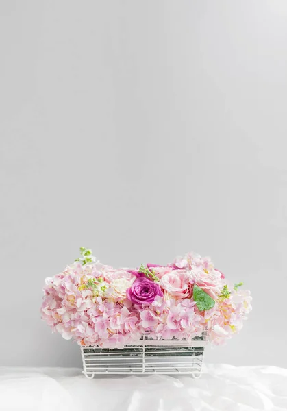 灰色の壁の前にテーブル クロスの上の花のバスケット — ストック写真