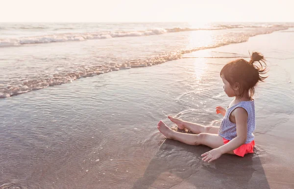Little girl 2-3 years plays on the beach in sunset — Stock Photo, Image