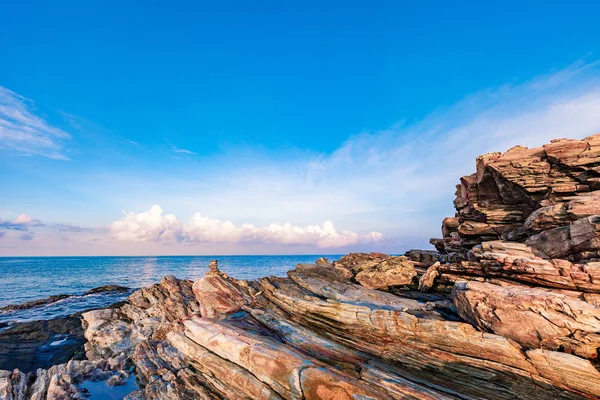 Rocky seashore in morning sunrise with bright blue sky and clouds — Stock Photo, Image