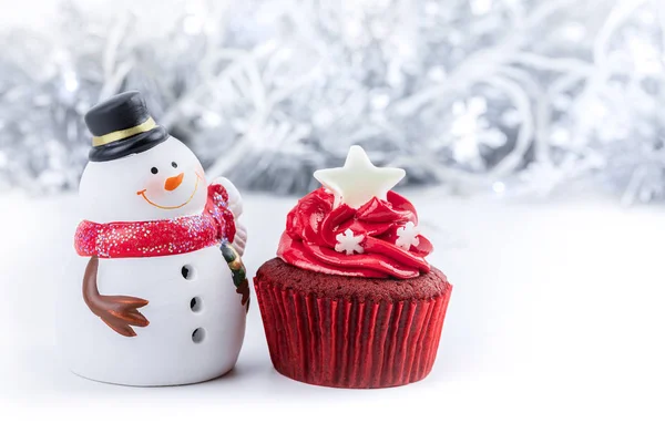 Καλά Χριστούγεννα και Καλή Χρονιά με κόκκινο cupcake και χιονάνθρωπο αγαλματίδιο — Φωτογραφία Αρχείου