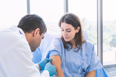 Asyalı doktor, güzel hasta kadına onu hastalıktan korumak için şırınga enjekte ediyor.