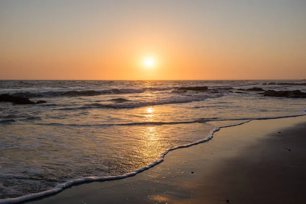 Bunter namibischer Sonnenuntergang mit tiefstehender Sonne und kleinen Wellen Stockbild