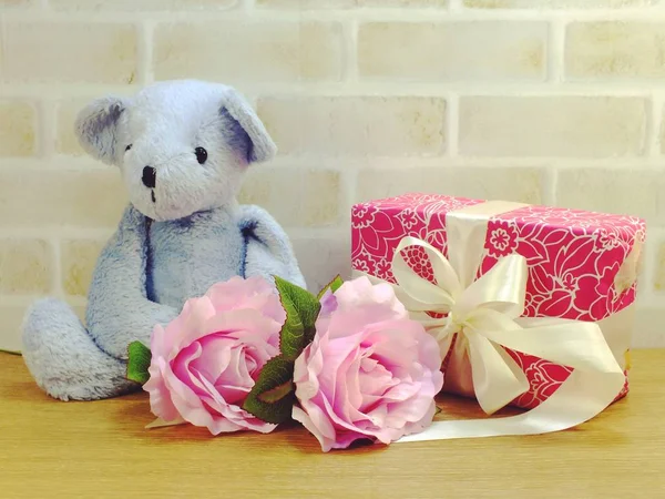 cute teddy bear doll with gift box and flowers with copy space