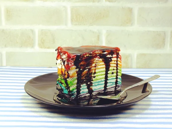 Rebanada de pastel de arco iris con salsa de chocolate — Foto de Stock