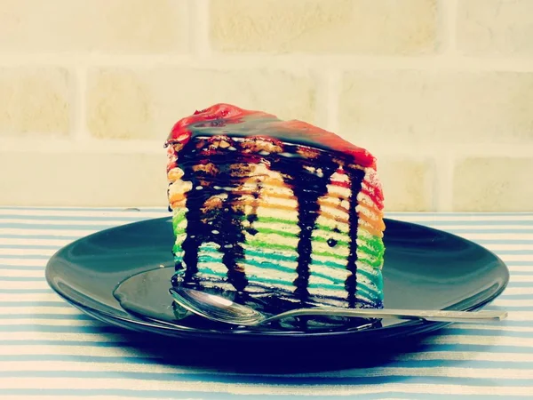 Rebanada de pastel de arco iris con salsa de chocolate — Foto de Stock