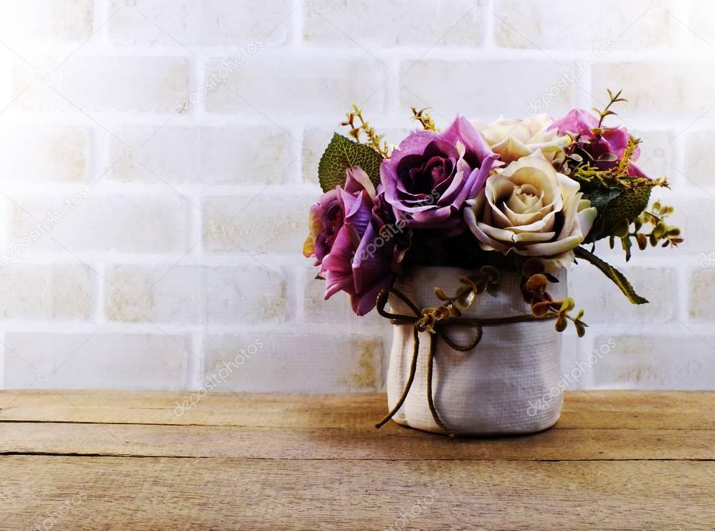 artificial rose flowers in vase on wooden and space wallpaper
