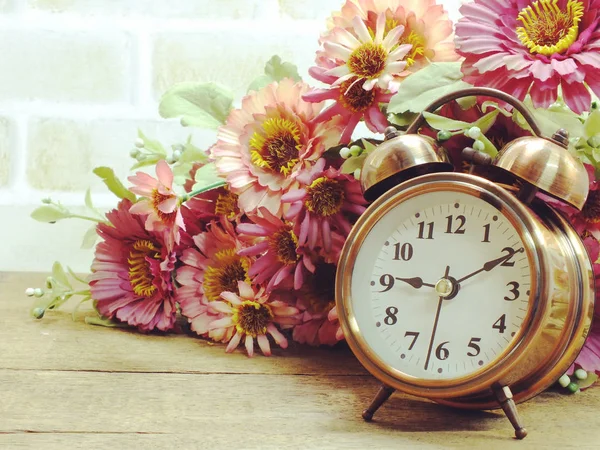 Spring time with alarm clock and artificial flowers bouquet background — Stock Photo, Image