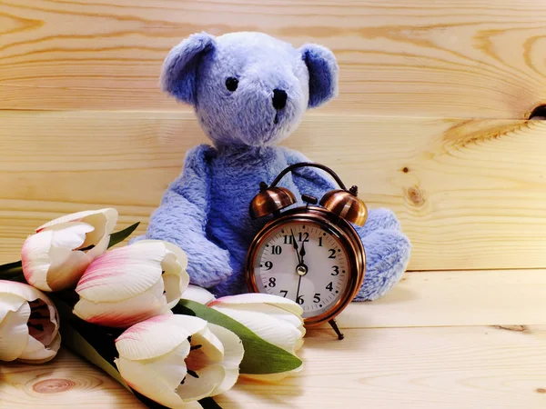 Tedy dragen met wekker en boeket bloemen op houten achtergrond — Stockfoto